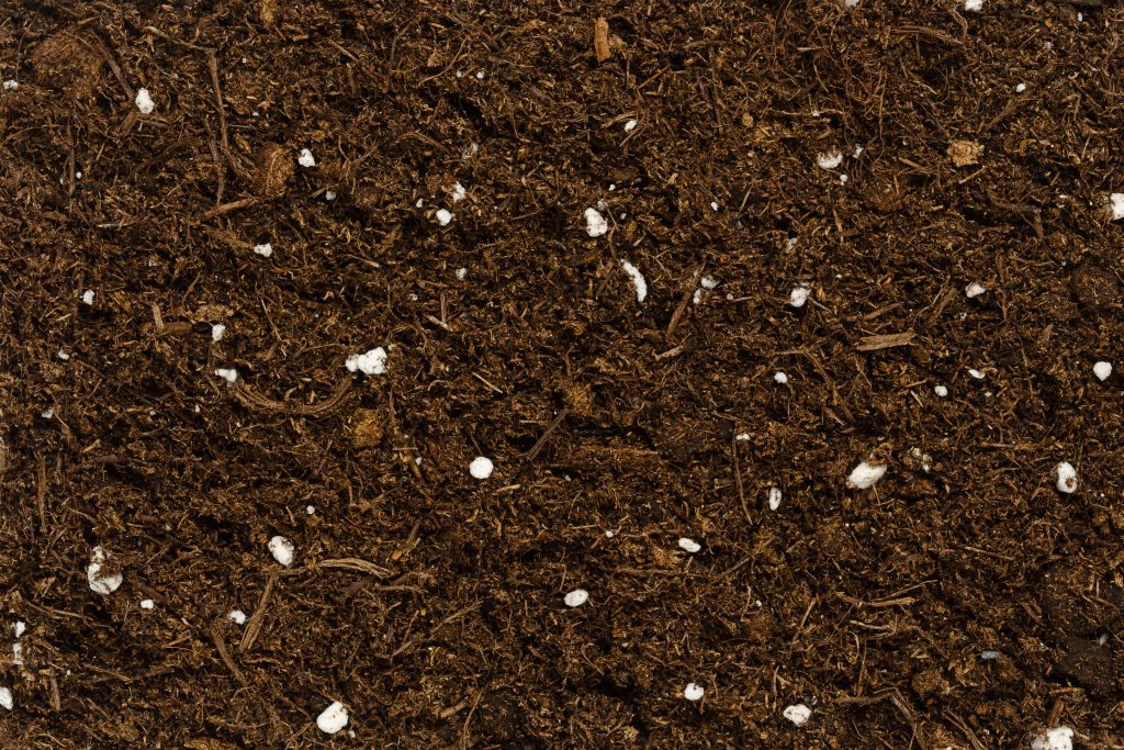 Organic potting compost, background, from above. Soil, growing medium and culture substrate for sowing. Made of moderately decomposed raised bog peat, bark humus, wood fibers, sand and NPK fertilizer.